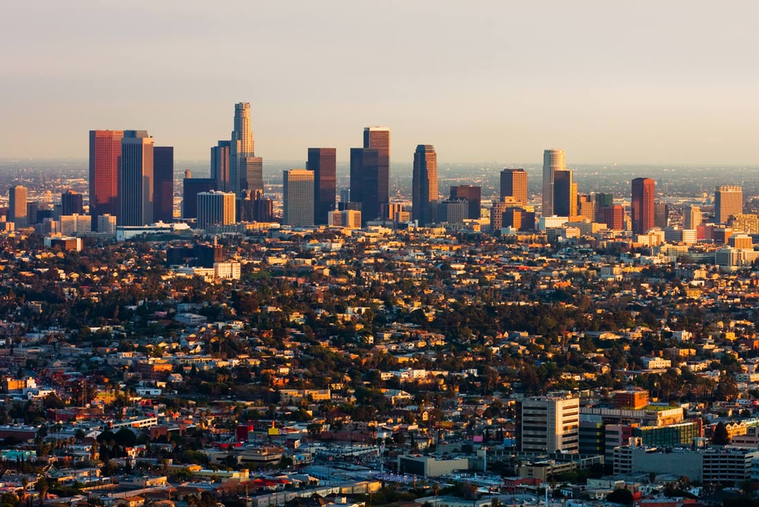 A cityscape view of a large city with many skyscrapers and buildings, taken at sunset.