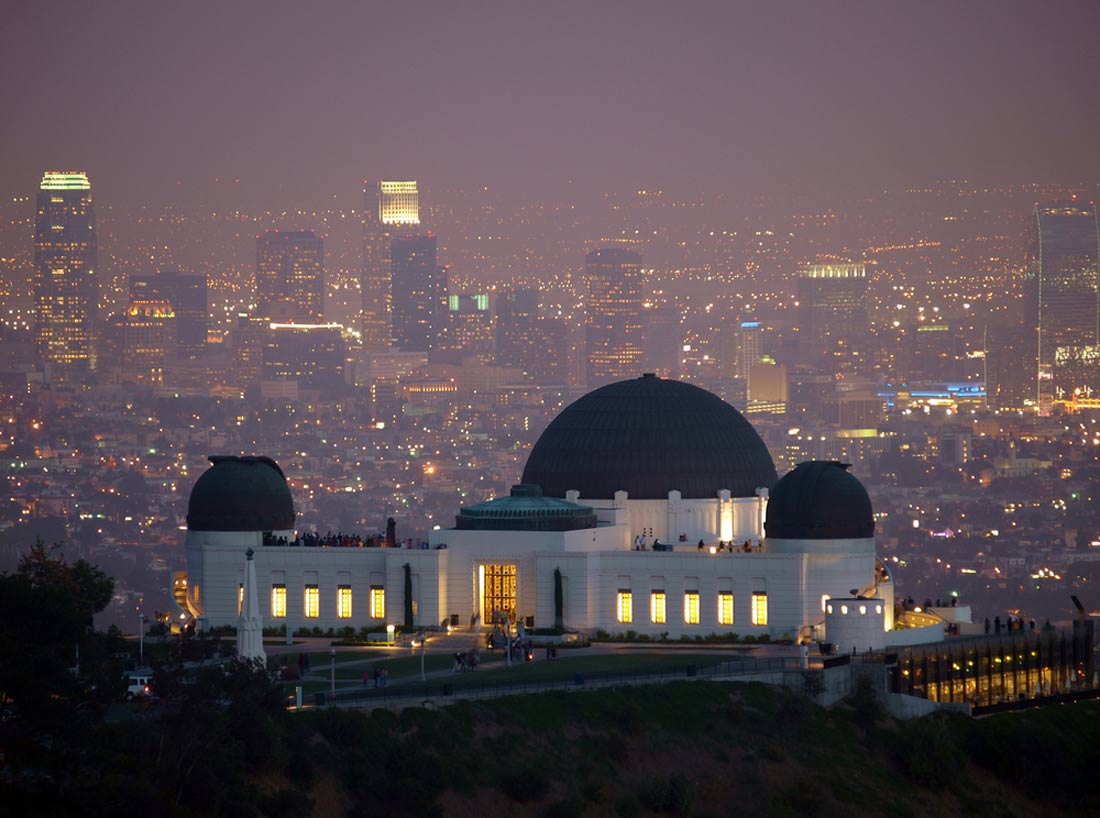 a cityscape at night with a large white building featuring domes